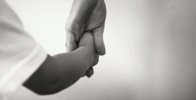 adult holding the hand of a child