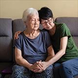 adult daughter with arms around aging mother