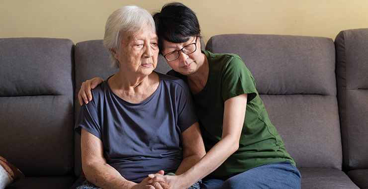 adult woman with arms around aging mother