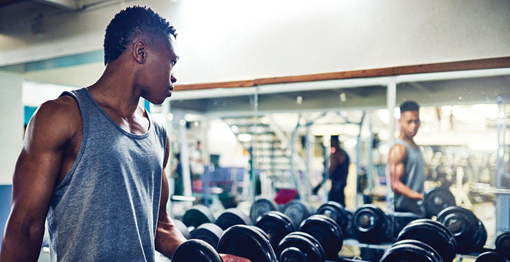 young man looking in the mirror lifting weights