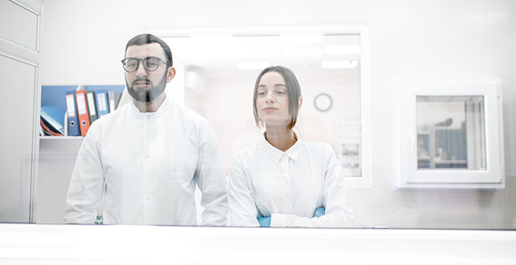 two researchers looking at a subject through glass