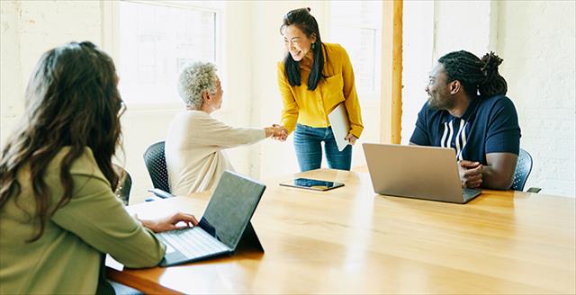 woman shaking hands with another woman in a conference room