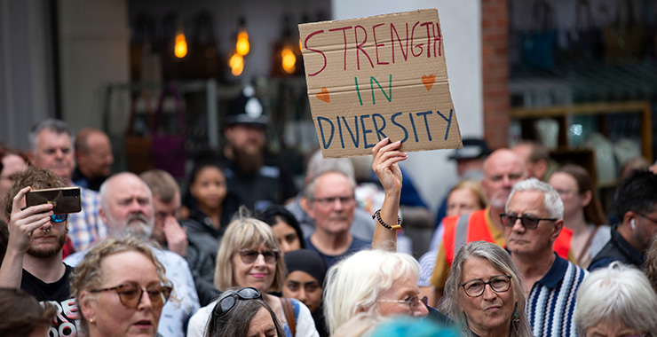 crowd of people with someone holding up a cardboard sign