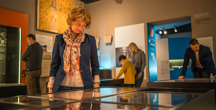 woman looking down at an exhibit behind glass