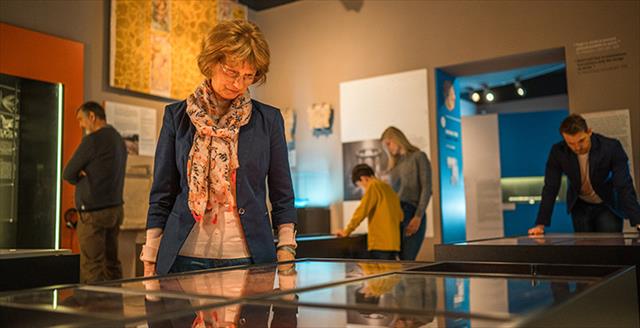 woman looking down at an exhibit behind glass