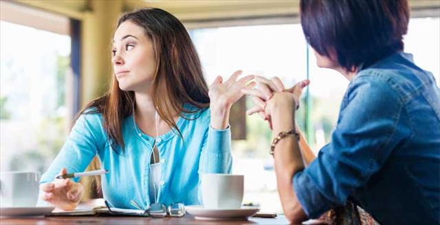 One woman is making a gesture toward another woman, indicating that she doesn't believe what the second woman is saying
