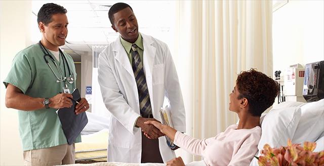 medical professional shaking hands with a patient in bed