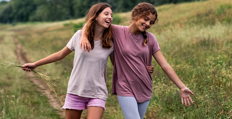 two girls walking arm and arm outside