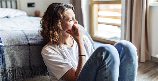 woman sitting on floor looking worried