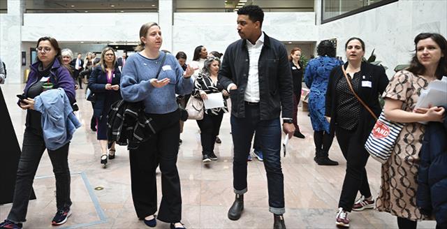 two people talking in the midst of a larger crowd of people milling about