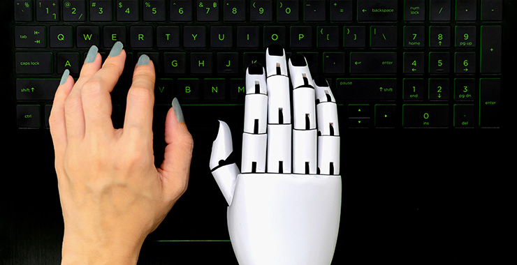 human hand and robotic hand together at a keyboard