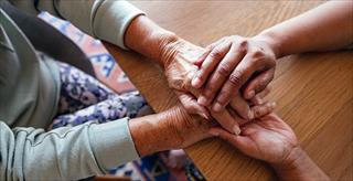 younger hands holding the hands of an older person