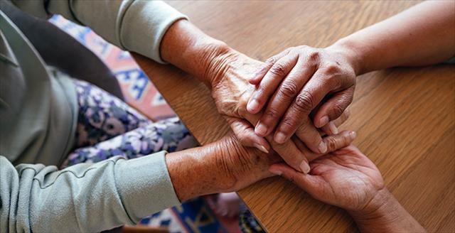 younger hands holding the hands of an older person