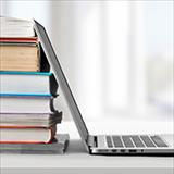 stack of books with open laptop leaning against it