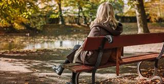 lonely woman sitting on park bench