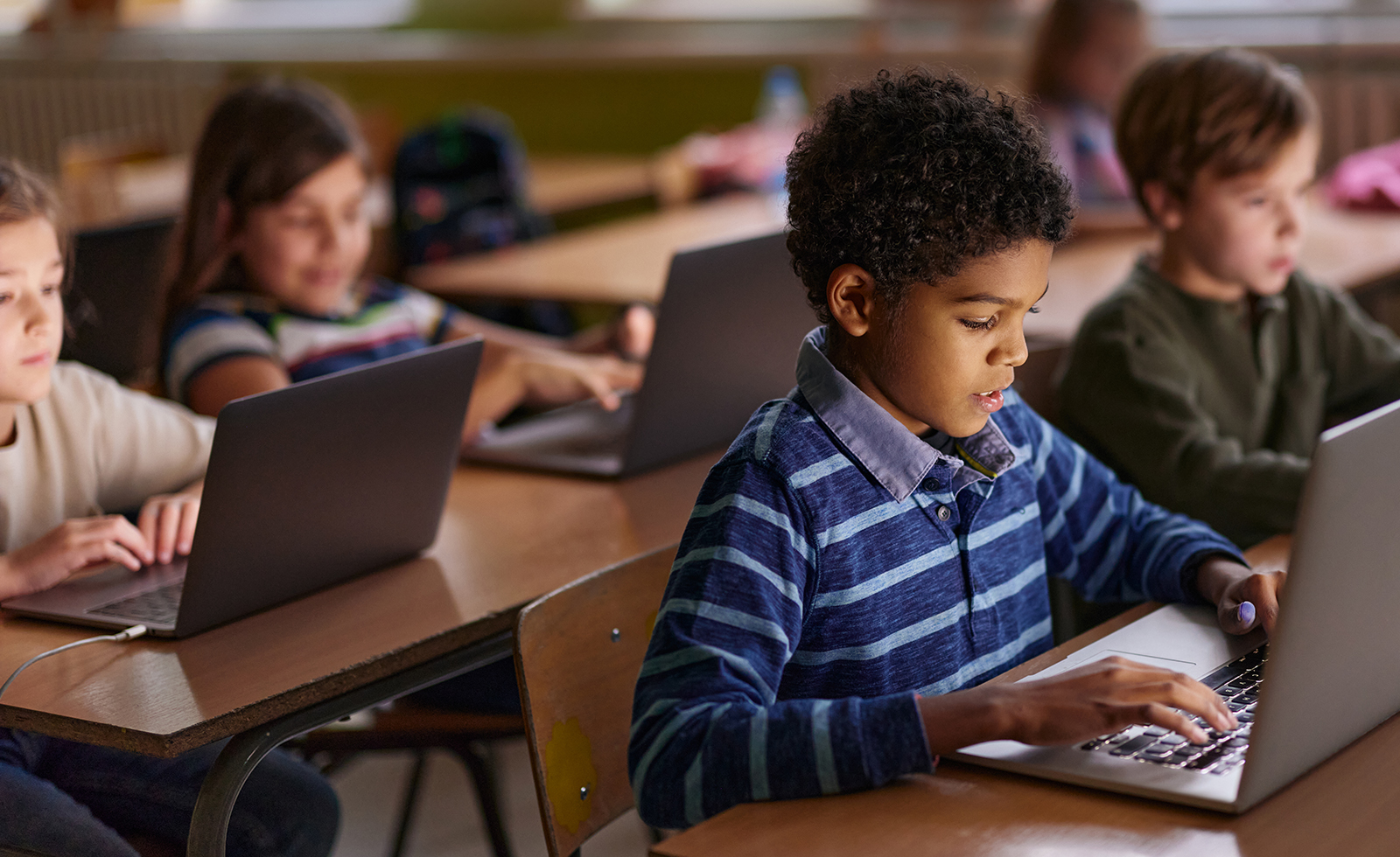 African American elementary student and his friends studying over computers during a class in the classroom