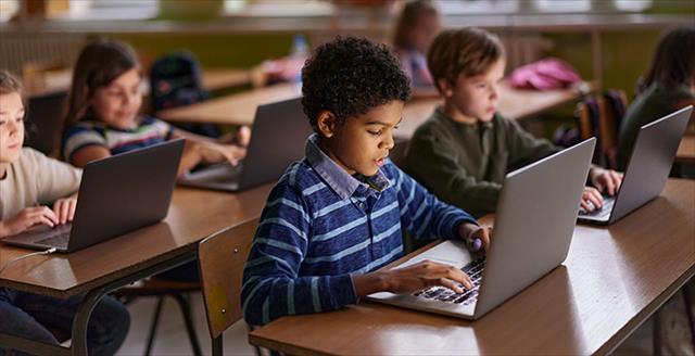 African American elementary student and his friends studying over computers during a class in the classroom