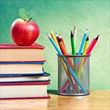 apple on top of stack of books next to pencil cup