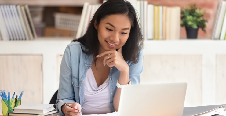 Young woman smiling as she looks at her laptop