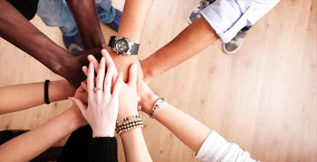 Group of hands layered on top of each other representing teamwork