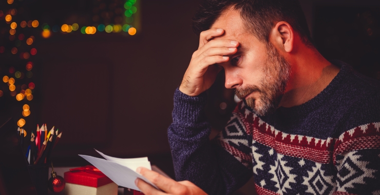 Man in Christmas sweater looking at a bill