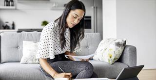 Woman sitting on couch taking notes
