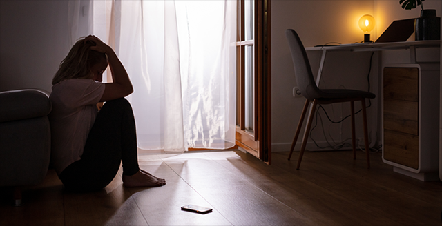 Woman sitting against her bed