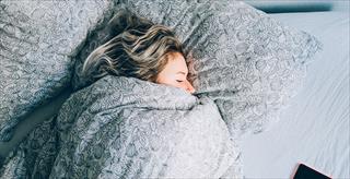 Woman sleeping in bed underneath covers