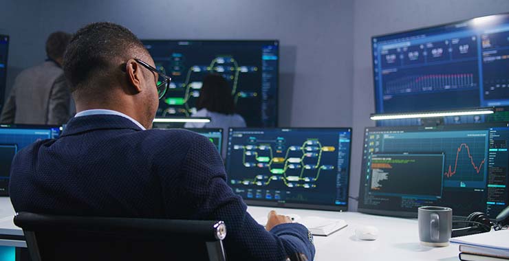 male employee looking at multiple computer screens