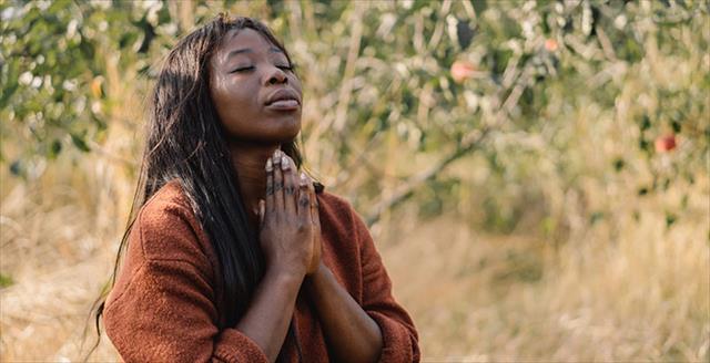 young African American woman praying outdoors