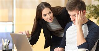 Boss scolding a shameful employee at work in an office