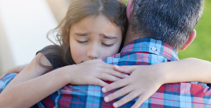 sad little girl being consoled by her father