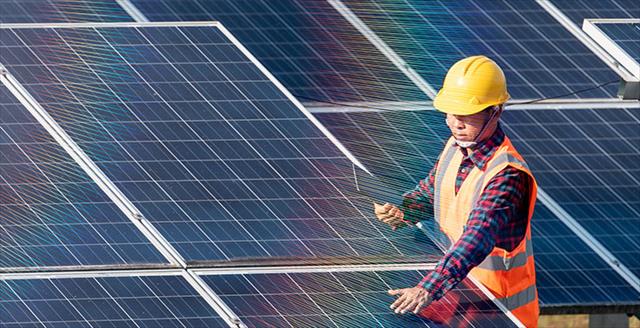 worker in a hard hat adjusting a solar panel