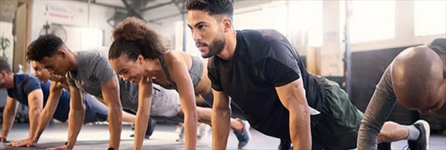 Gym with men and women exercising for muscle, cardio, and endurance.