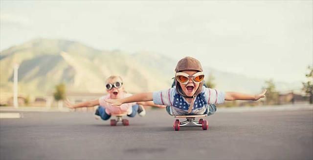 children riding on skateboards pretending they are airplanes