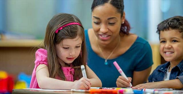 young children work at the table while teacher observes