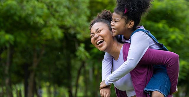 mother giving her young daughter a piggyback ride