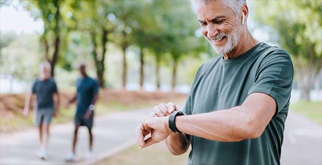 senior man looking at smartwatch during a run outside