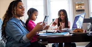 Mother with daughters doing schoolwork at home.