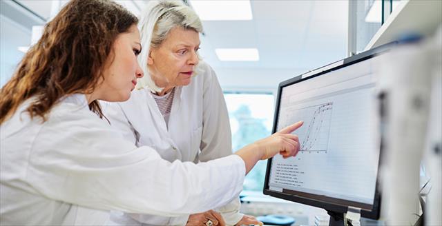Photograph of two scientists reviewing data on computer screen