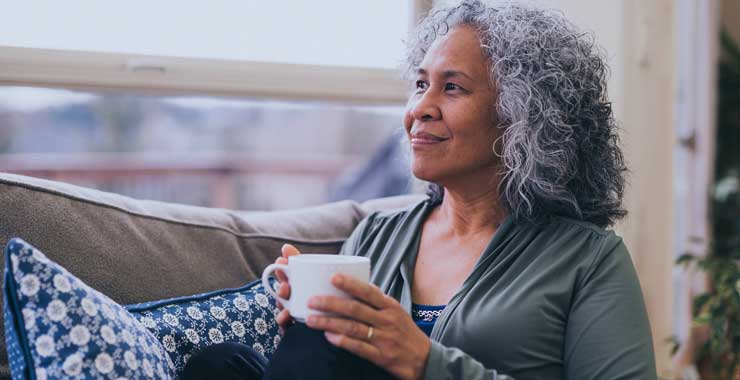 Thoughtful-looking elderly woman holding a coffee mug