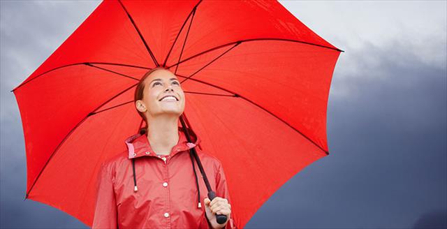 smiling young woman standing outside while holding her red umbrella