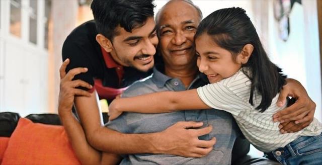 Children smiling and hugging their father.
