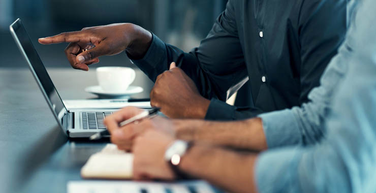 A generic image of a hand holding a cup of coffee with a laptop near.
