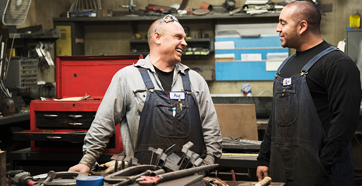 two auto mechanics talking in garage