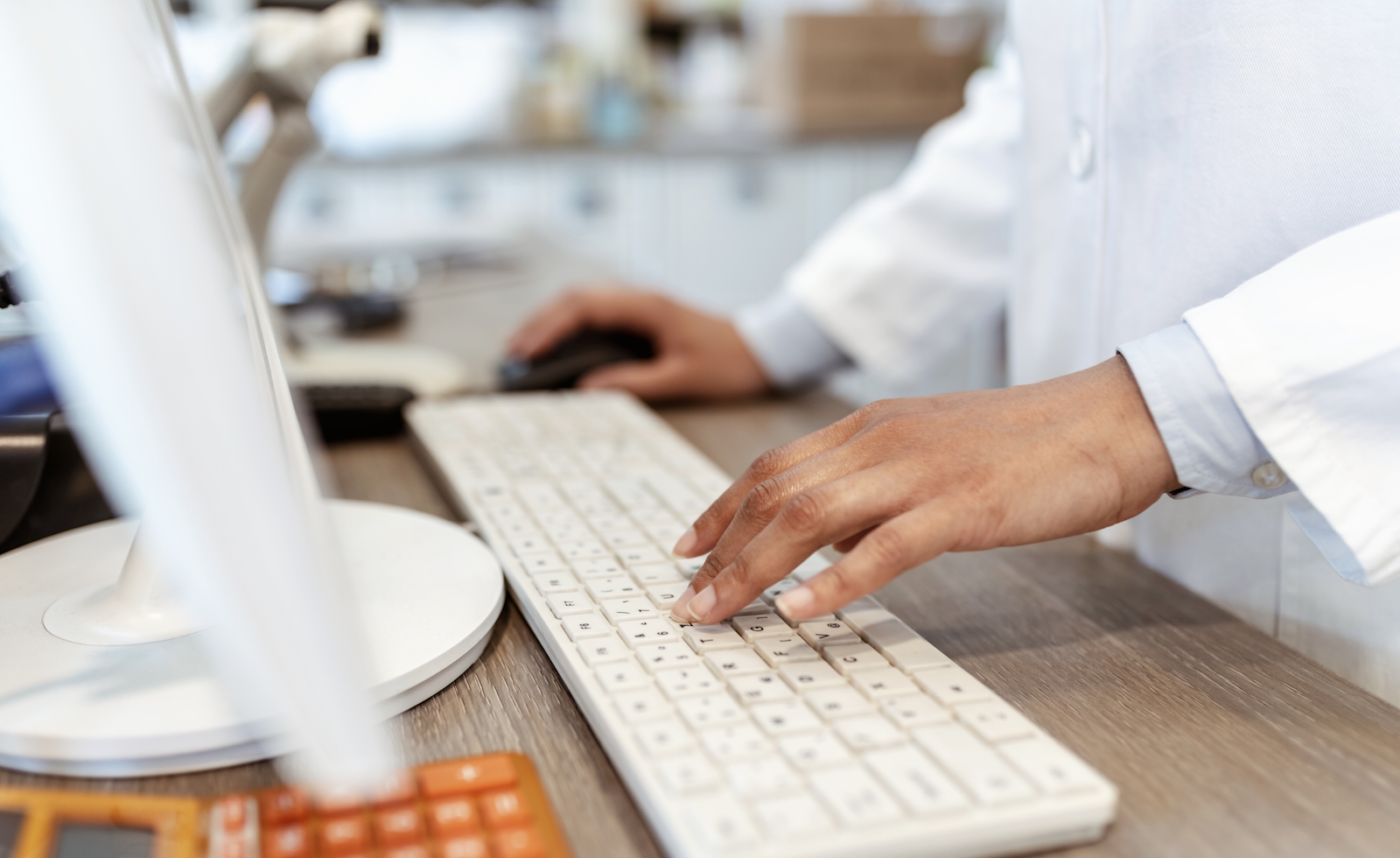 Closeup of pharmacist's hands typing on a computer keyboard at the pharmacy counter