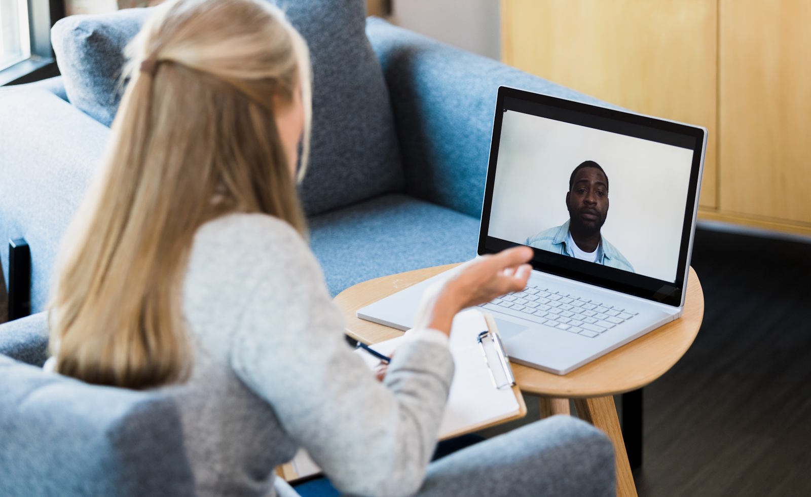 Woman conducts telehealth counseling session, using laptop, taking notes