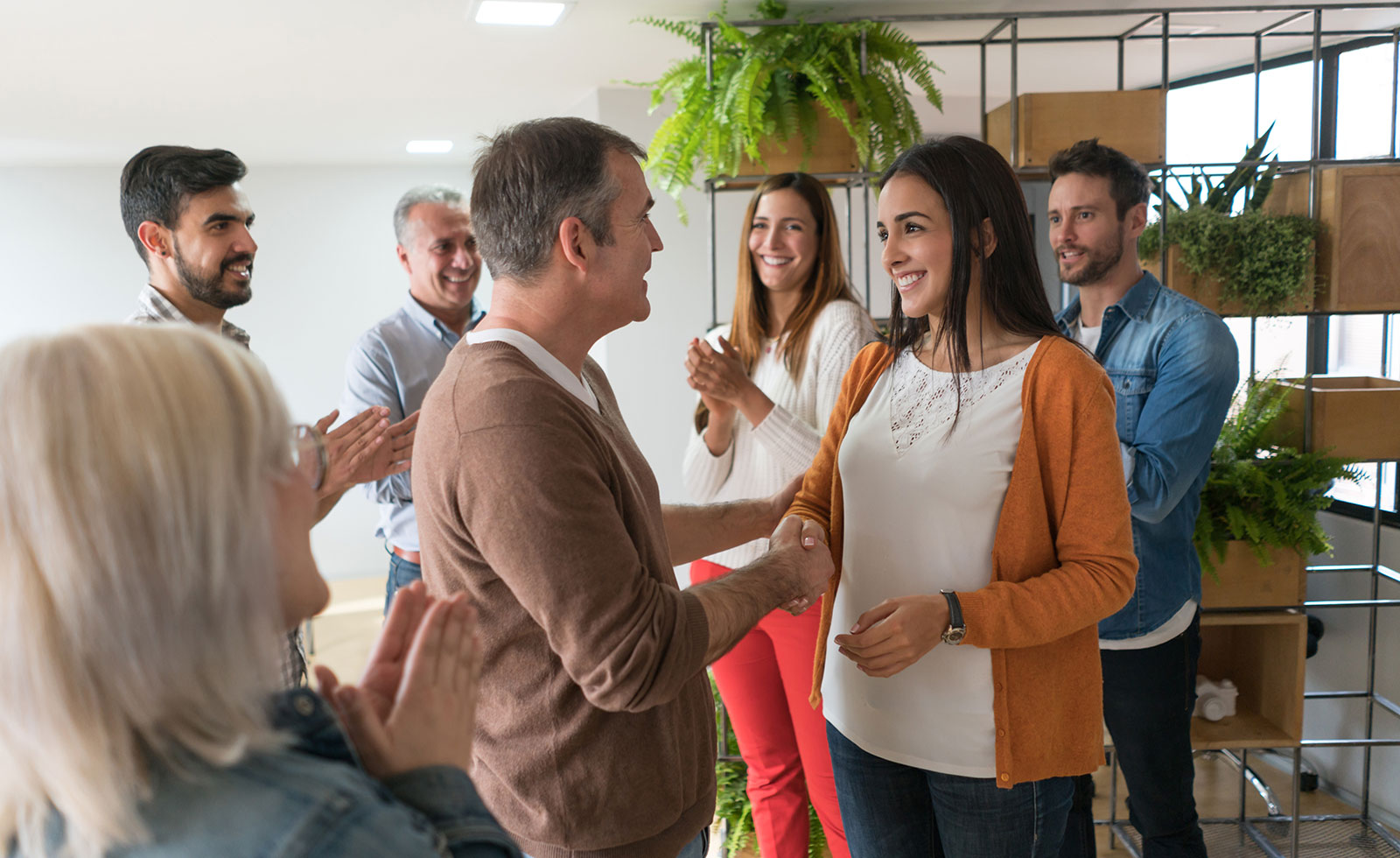 Man handshaking a woman at the office celebrating her promotion