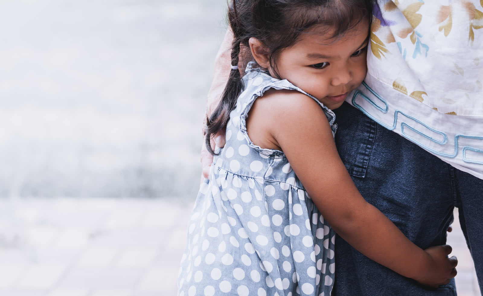 Girl clinging to mother's leg