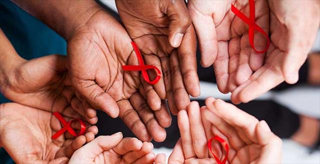 group of multiracial people holding red ribbon for AIDS HIV awareness
